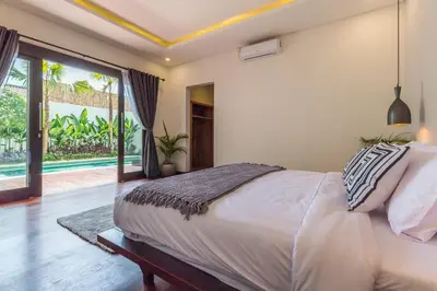 a bedroom with a large bed and a large window at Villa Azura in Seminyak