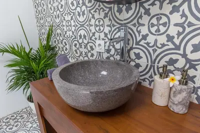 a bathroom with a stone sink on a wooden counter at Villa Azura in Seminyak