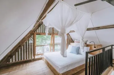 a bedroom with a white bed with a canopy at Chanteak Bali in Jimbaran