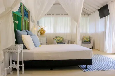 a bedroom with a bed with curtains and a television at Chanteak Bali in Jimbaran