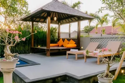 a garden with a gazebo and chairs and a pool at The Lavana Arimanu Kuta in Kuta