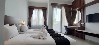 a hotel room with two beds and a desk at Pondok DenAyu Homestay in Kuta