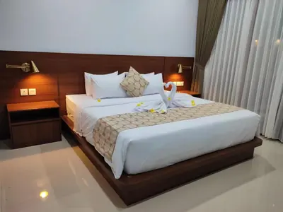 a bedroom with a large bed with white sheets at Pondok DenAyu Homestay in Kuta
