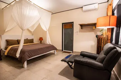 a bedroom with a bed and a couch and a chair at Villa Janitra in Seminyak