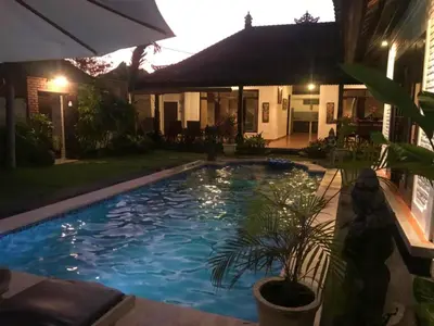 a swimming pool in front of a house at night at Tegal Uma Seminyak by Maha Bali in Seminyak