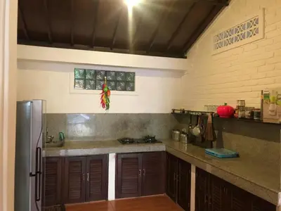 a kitchen with wooden cabinets and a stainless steel refrigerator at Tegal Uma Seminyak by Maha Bali in Seminyak