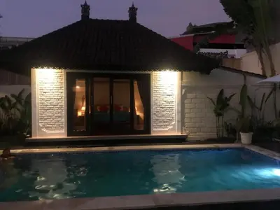 a swimming pool in front of a house at night at Tegal Uma Seminyak by Maha Bali in Seminyak