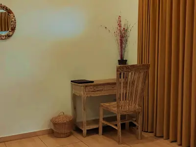 a wooden desk with a chair next to a curtain at Tegal Uma Seminyak by Maha Bali in Seminyak