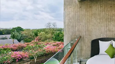 a room with a bed and a balcony with flowers at RIMBA by AYANA Bali in Jimbaran