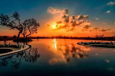 two boats on a river with the sunset in the background at RIMBA by AYANA Bali in Jimbaran