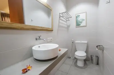 a white bathroom with a sink and a toilet at The jero 18 kuta guest house in Kuta
