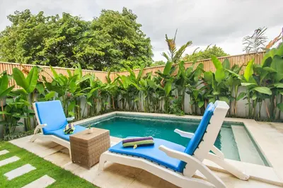 a backyard with two chairs and a swimming pool at The jero 18 kuta guest house in Kuta