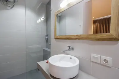 a white bathroom with a sink and a mirror at The jero 18 kuta guest house in Kuta