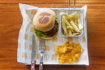 a tray with a hamburger and chips on a table at The jero 18 kuta guest house in Kuta