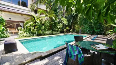 a swimming pool with a table and chairs next to a house at Villa Bali Maja - Beautiful Private Pool Villa in Petitenget, Seminyak in Seminyak
