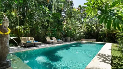 a swimming pool in a garden with chairs and trees at Villa Bali Maja - Beautiful Private Pool Villa in Petitenget, Seminyak in Seminyak