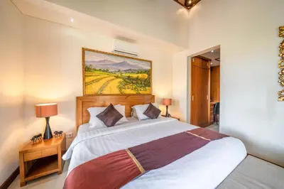 a bedroom with a bed and a painting on the wall at Villa Seacluded 1 - 3BR Villa in Central Seminyak - Large Pool in Seminyak