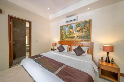 a bedroom with a large bed and a painting on the wall at Villa Seacluded 1 - 3BR Villa in Central Seminyak - Large Pool in Seminyak