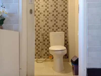 a bathroom with a white toilet in a room at Simple Kuta Bedroom in Kuta