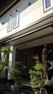 a house with two potted trees in front of it at Simple Kuta Bedroom in Kuta