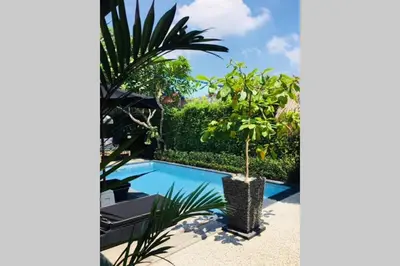 a pool with a palm tree next to a house at Villa Bloom 4 - 2 King bedrooms , Sleep 4 Pax, private pool, Seminyak in Seminyak