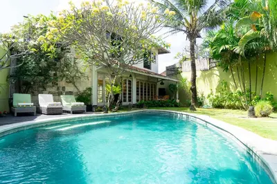a swimming pool in front of a house at Villa Noretsy in Seminyak