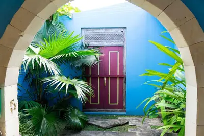 a red door in a blue wall with palm trees at Villa Noretsy in Seminyak