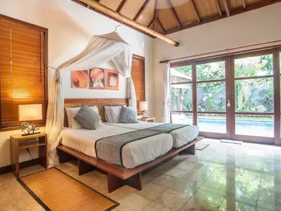 a bedroom with a bed with a canopy at Mango Tree Villas Jimbaran Bali in Jimbaran