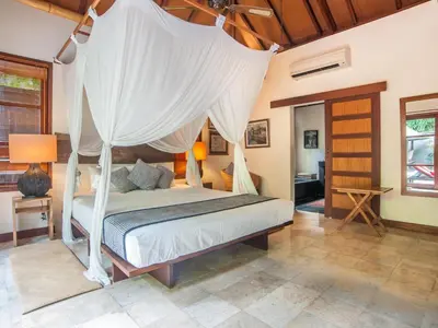 a bedroom with a bed with a canopy at Mango Tree Villas Jimbaran Bali in Jimbaran