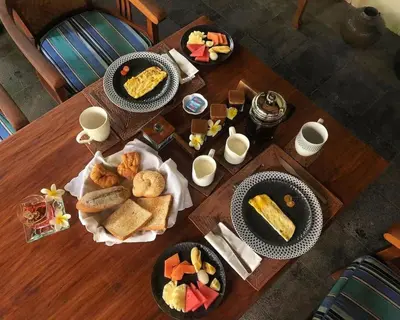 a wooden table with plates of food on it at Mango Tree Villas Jimbaran Bali in Jimbaran