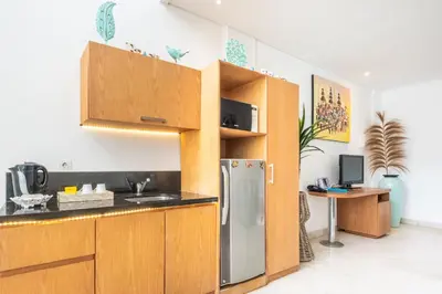 a kitchen with wooden cabinets and a stainless steel refrigerator at AQ-VA Hotel & Villas Seminyak in Legian