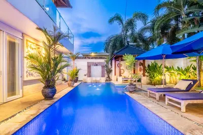 a swimming pool in the backyard of a house with blue umbrellas at AQ-VA Hotel & Villas Seminyak in Legian