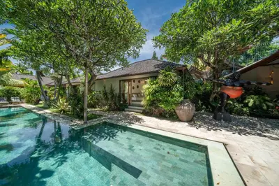 a swimming pool in front of a house with trees at Villa Teman - Luxury 4BR Villa in Central Seminyak - HUGE POOL in Seminyak