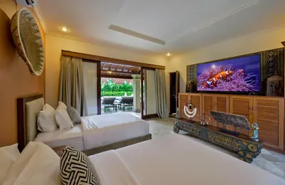 a hotel room with two beds and a flat screen tv at Villa Deh Simba at Oberoi in Seminyak