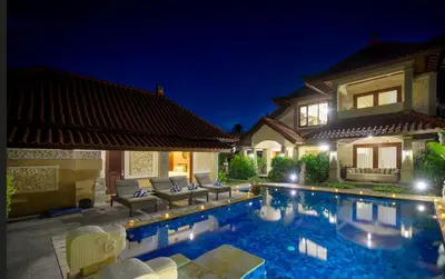 a swimming pool in front of a house at night at Villa Deh Simba at Oberoi in Seminyak