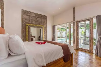 a bedroom with a white bed and a mirror at Villa Alegria in Seminyak