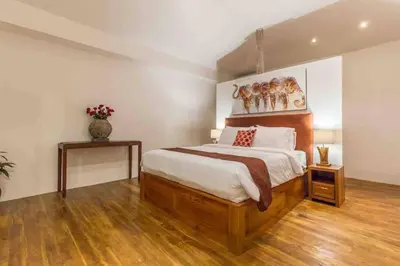 a bedroom with a large bed and wooden floors at Villa Alegria in Seminyak