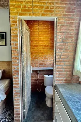 a brick bathroom with a toilet in a brick wall at Bali Eco Living Yoga Healing Meditation and Retreat Center in Denpasar