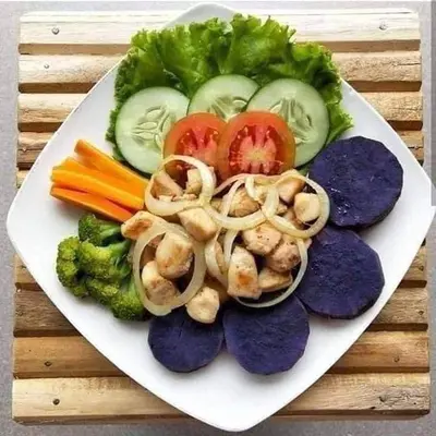 a plate of vegetables and shrimp on a wooden table at Bali Eco Living Yoga Healing Meditation and Retreat Center in Denpasar