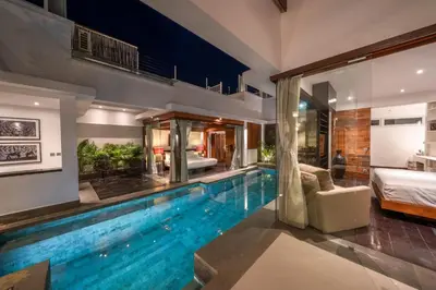 a swimming pool in a house with a bedroom at Villa Tykhe - Modern Balinese 4BR Pool Villa in Central Seminyak in Seminyak