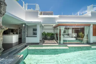 a house with a swimming pool and a kitchen at Villa Tykhe - Modern Balinese 4BR Pool Villa in Central Seminyak in Seminyak