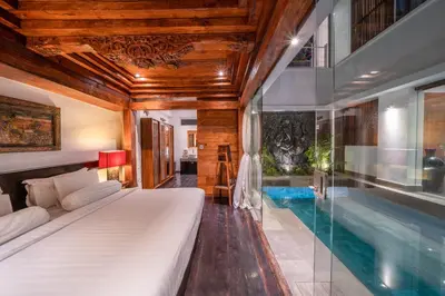 a bedroom with a bed and a swimming pool at Villa Tykhe - Modern Balinese 4BR Pool Villa in Central Seminyak in Seminyak