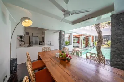 a kitchen and dining room with a wooden table and chairs at Villa Tykhe - Modern Balinese 4BR Pool Villa in Central Seminyak in Seminyak