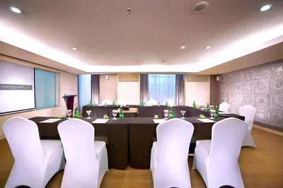a conference room with a table and white chairs at Harper Kuta Hotel by ASTON in Legian