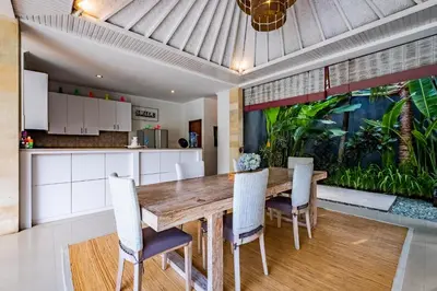 an open kitchen and dining room with a wooden table and chairs at Central Seminyak Villa Martini in Seminyak