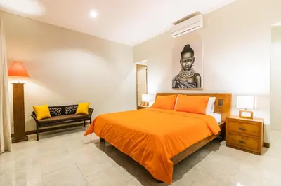 a bedroom with a large orange bed and a chair at Listien Villa N3 in Seminyak