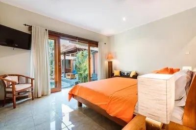 a bedroom with an orange bed and a balcony at Listien Villa N3 in Seminyak