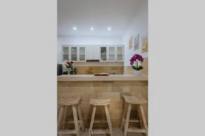 a kitchen with stools and a counter with white cabinets at Villa Cathy, Seminyak - Private 3 Bedroom Pool Villa! in Seminyak