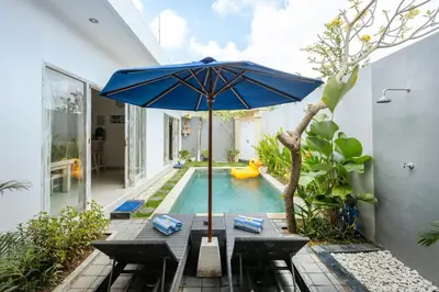 a table with an umbrella next to a swimming pool at Villa Cathy, Seminyak - Private 3 Bedroom Pool Villa! in Seminyak