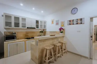 a kitchen with bar stools and a clock on the wall at Villa Cathy, Seminyak - Private 3 Bedroom Pool Villa! in Seminyak